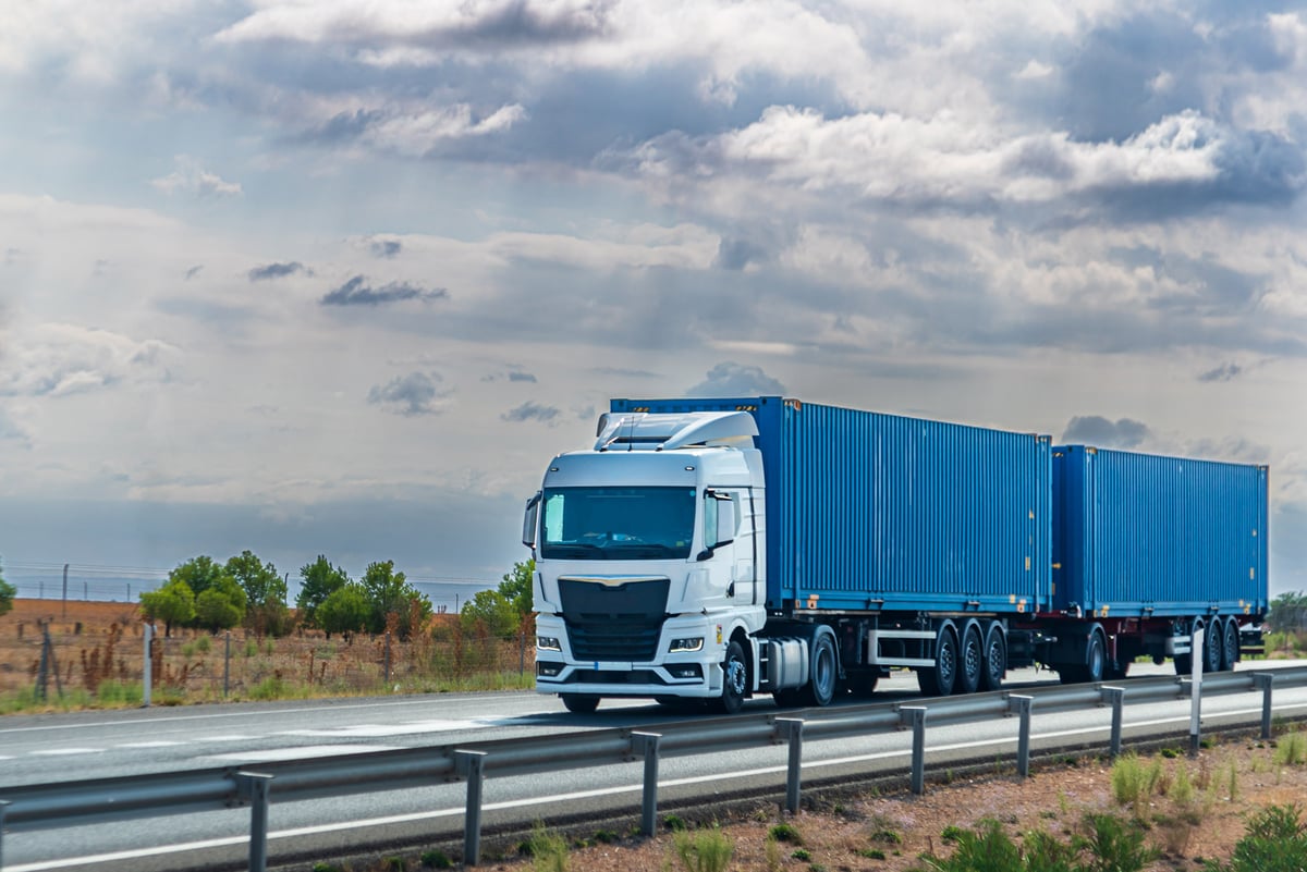 Camion transportant deux conteneurs bleus sur une autoroute