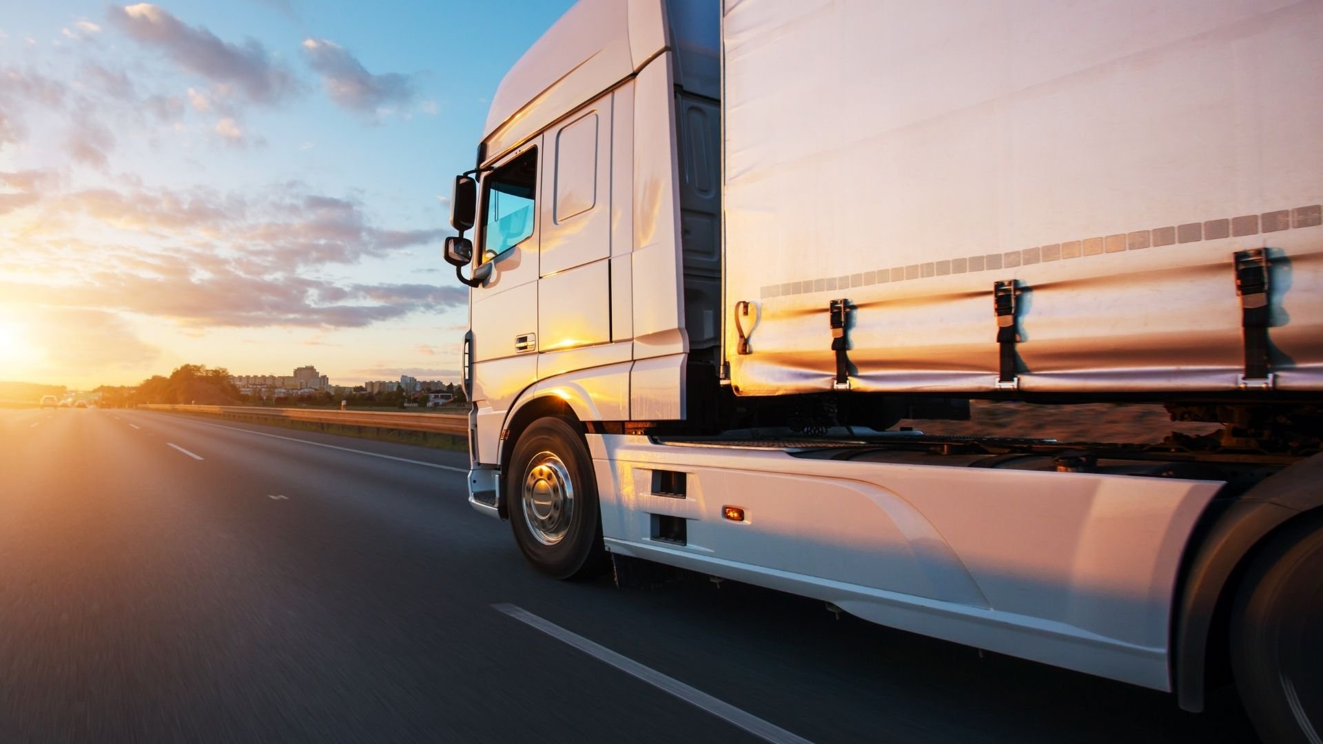 Lorry driving along road at sunset