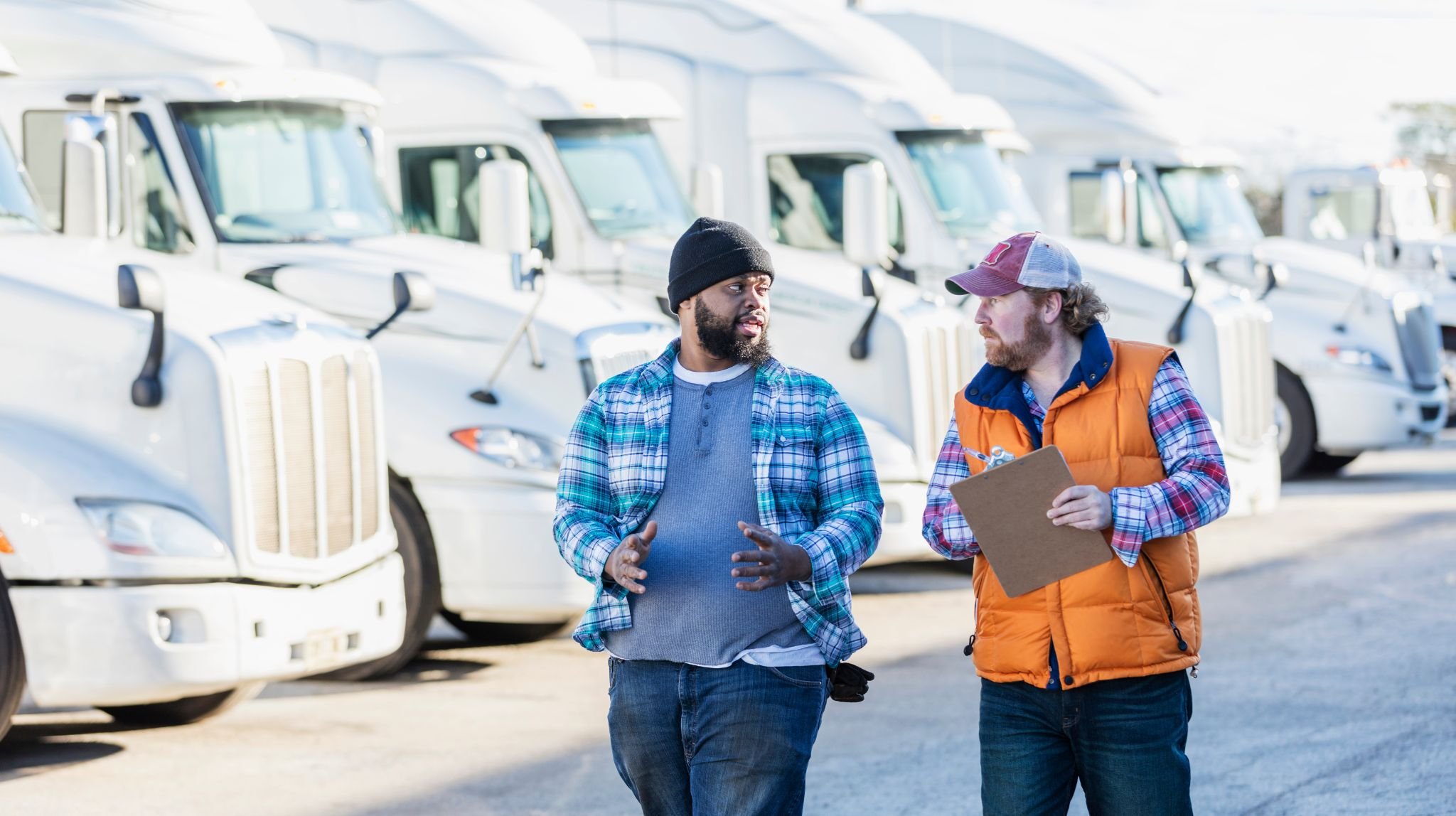Two drivers talking in front of a row of trucks