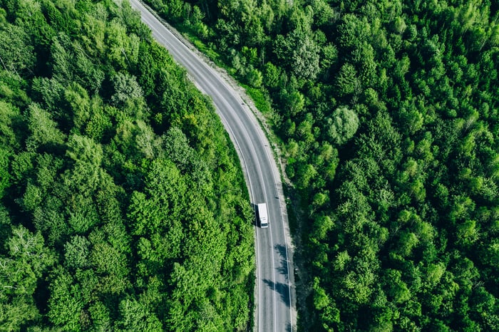 Aerial view of a truck on a road through a forest