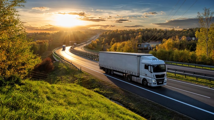 Trucks on a motorway winding through a forest