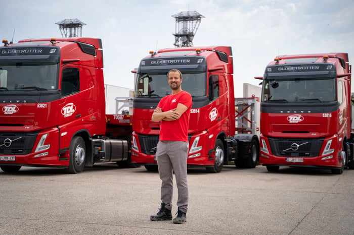 Chauffeur de TDL Group devant des camions rouges