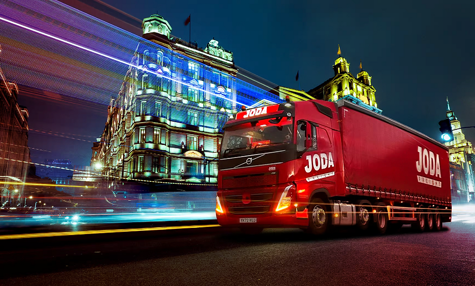 Red JODA Freight truck at night in front of illuminated city buildings