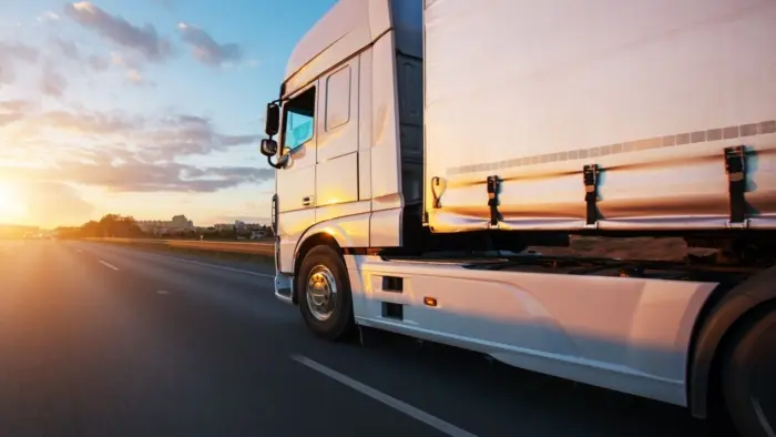 Lorry driving along road at sunset