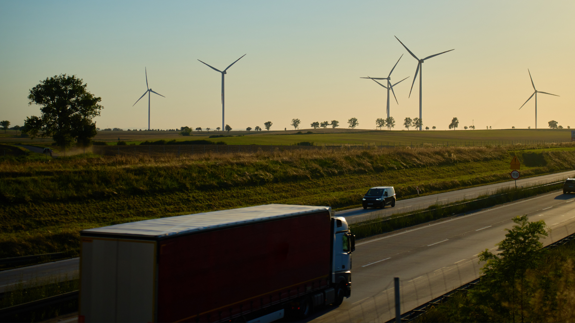 Lorry driving on road next to wind turbines